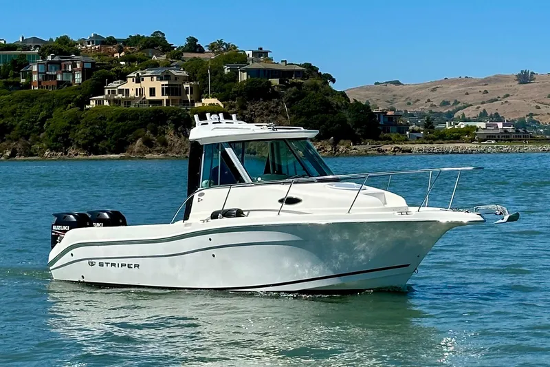 Slide: The Image of 2013 Seaswirl Striper 2601 Walkaround O/B boat on scenic waterway with hillside homes. - 1