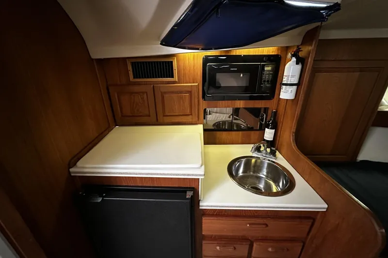 Slide: The Image of 1997 Luhrs 32 Open yacht galley with sink, microwave, and storage cabinets. - 22