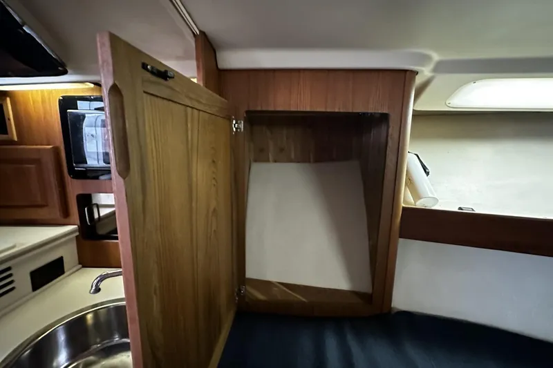 Slide: The Image of 1997 Luhrs 32 Open interior with open wooden cabinet and sink. - 31