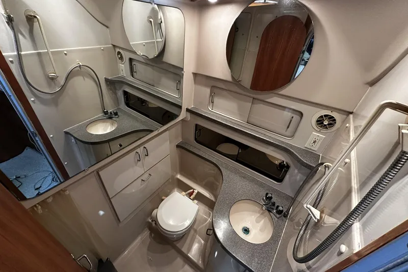 Slide: The Image of 1997 Luhrs 32 Open boat bathroom with sink, toilet, mirror, and storage cabinets. - 32