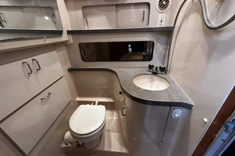 Slide: The Image of 1997 Luhrs 32 Open boat bathroom with sink, toilet, and storage cabinets. - 33