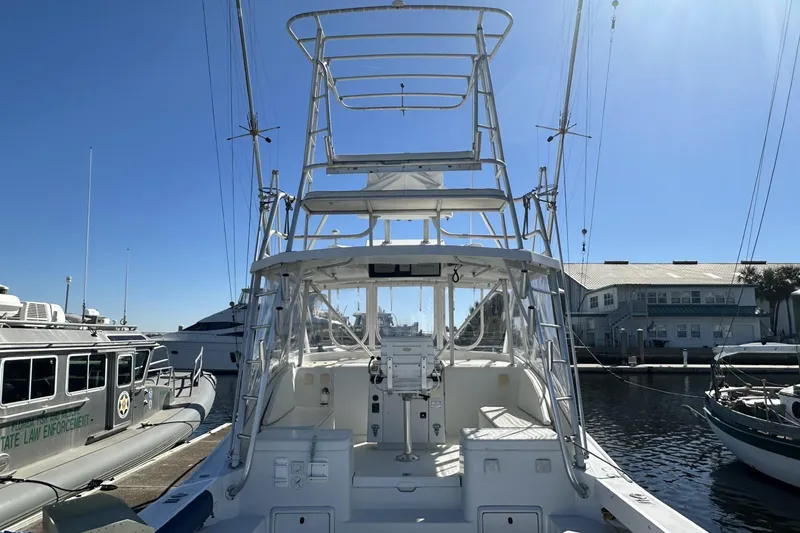 Slide: The Image of 1997 Luhrs 32 Open boat docked at marina, featuring a tall tower and clear skies. - 7