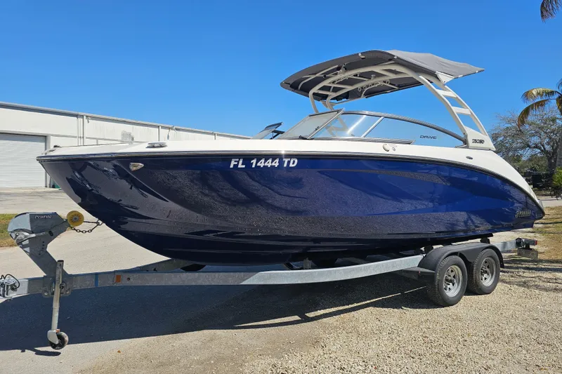 The Image of 2022 Yamaha Boats 252SD on trailer, blue hull, parked outdoors. - 0
