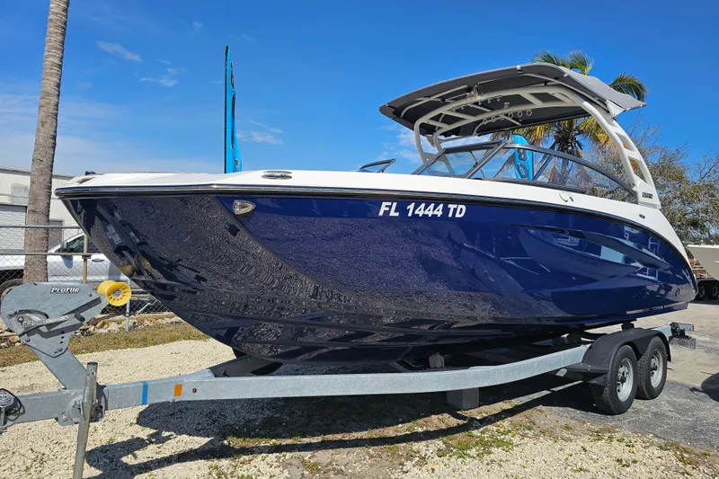 Slide: The Image of 2022 Yamaha Boats 252SD on trailer, sleek blue design, sunny day backdrop. - 10