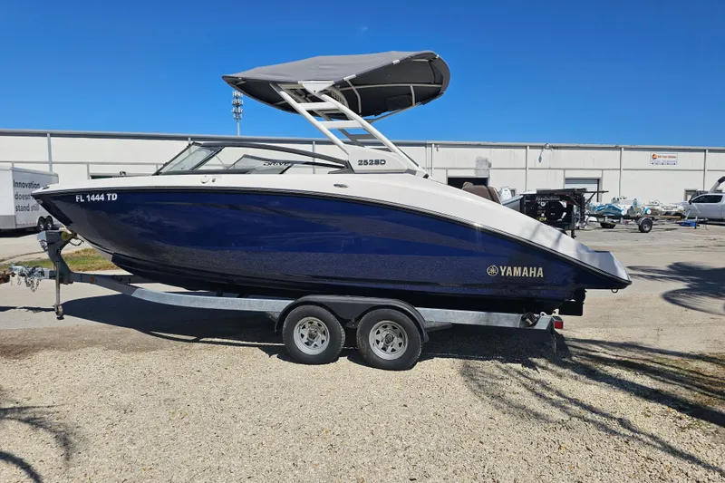 Slide: The Image of 2022 Yamaha Boats 252SD on trailer, blue and white, parked outdoors. - 2