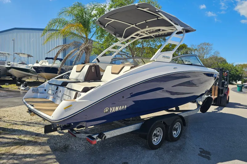 Slide: The Image of 2022 Yamaha Boats 252SD on trailer, sleek design, parked outdoors under blue sky. - 6