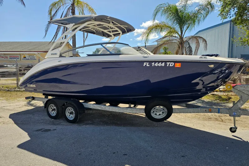 Slide: The Image of 2022 Yamaha Boats 252SD on trailer, parked outdoors with palm trees in background. - 8