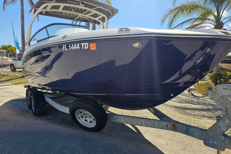 Slide: The Image of 2022 Yamaha Boats 252SD on trailer, parked outdoors with palm trees in background. - 9