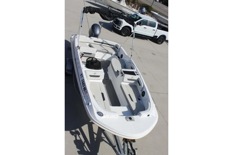 Slide: The Image of 2021 Hurricane SunDeck Sport 185 OB boat on trailer, parked beside a white truck. - 13