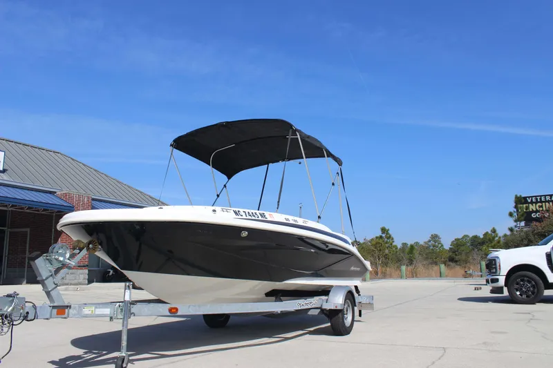Slide: The Image of 2021 Hurricane SunDeck Sport 185 OB boat on trailer, parked outdoors under clear blue sky. - 6