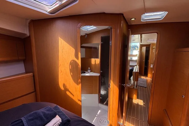 Slide: The Image of Interior of 2011 Jeanneau Sun Odyssey 44 yacht, featuring wood paneling and a compact bathroom. - 9