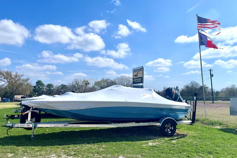 The Image of 2026 Xpress H20B Bay boat covered, on trailer, near flags and dealership sign. - 1