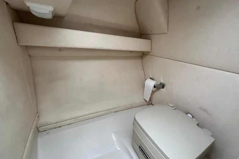 Slide: The Image of Interior of 2004 Sea Ray 220 Sundeck boat with compact toilet and storage shelf. - 16