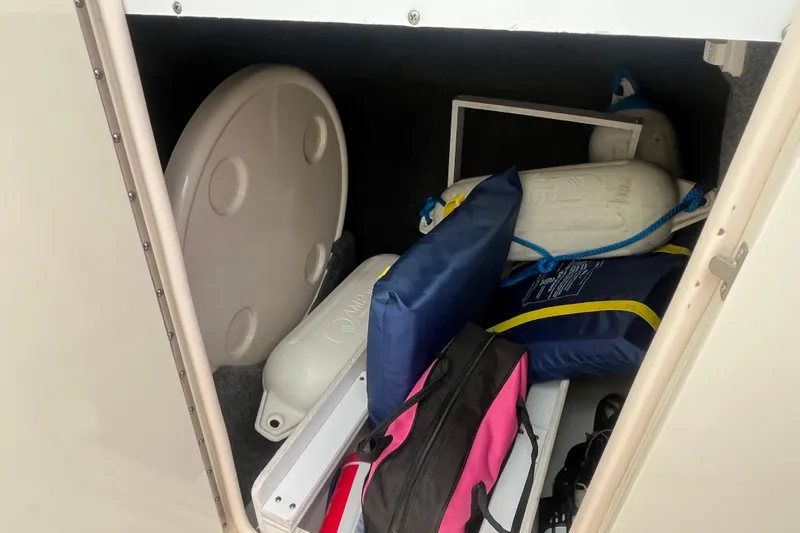 Slide: The Image of Storage compartment of 2004 Sea Ray 220 Sundeck with boating accessories and life jackets. - 19