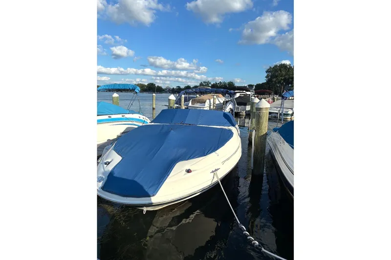 Slide: The Image of 2004 Sea Ray 220 Sundeck boat docked with blue cover under a clear sky. - 3