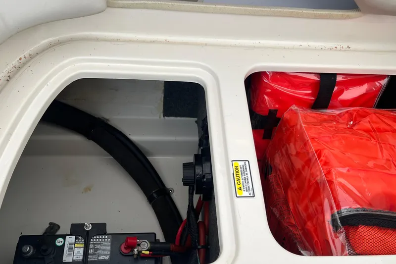 Slide: The Image of Storage compartment of 2004 Sea Ray 220 Sundeck with battery and life jackets. - 32