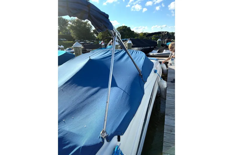 Slide: The Image of 2004 Sea Ray 220 Sundeck with blue cover docked on a sunny day. - 4