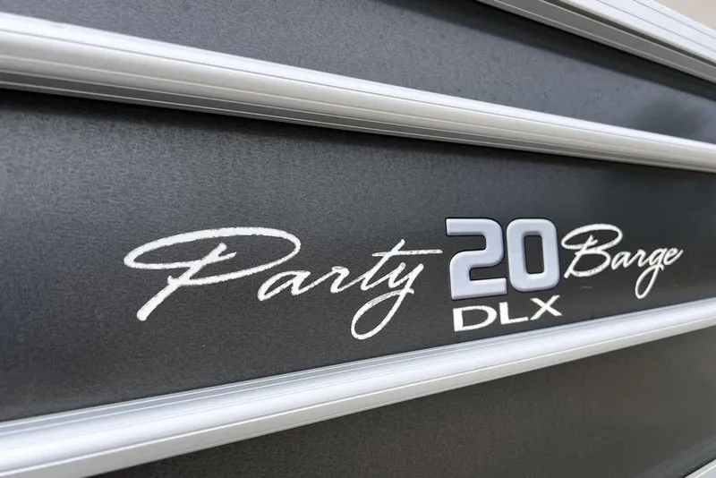 Slide: The Image of 2026 Sun Tracker Party Barge 20 DLX logo on sleek metallic surface. - 7