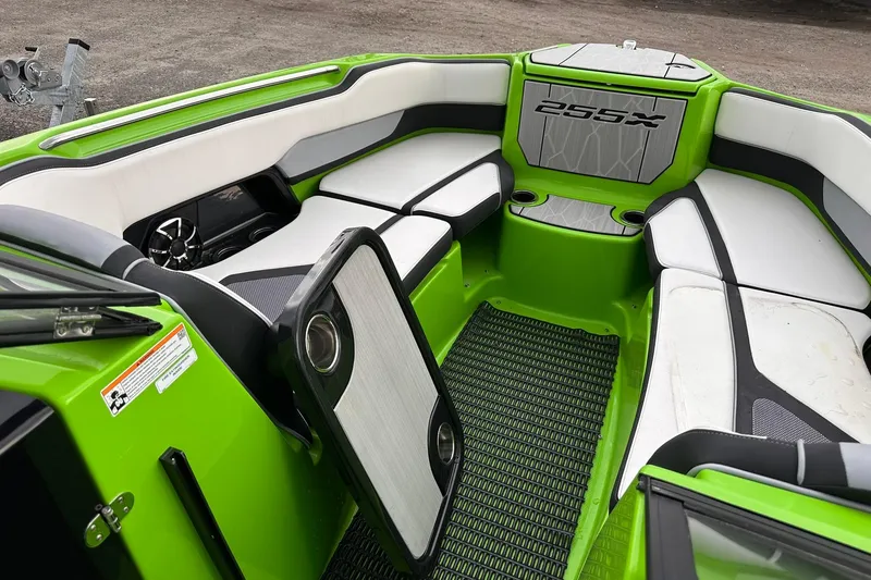 Slide: The Image of 2022 Yamaha Boats 255XD interior with green and white seating, cup holders, and speaker system. - 11