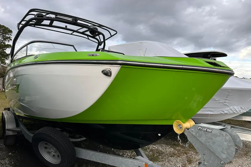 Slide: The Image of 2022 Yamaha Boats 255XD in vibrant green on a trailer, under cloudy skies. - 20