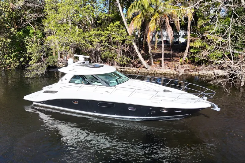 Slide: The Image of 2011 Sea Ray 450 Sundancer yacht cruising on a serene waterway surrounded by lush greenery. - 2