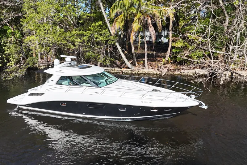 Slide: The Image of 2011 Sea Ray 450 Sundancer yacht cruising on a serene waterway, surrounded by lush greenery. - 3