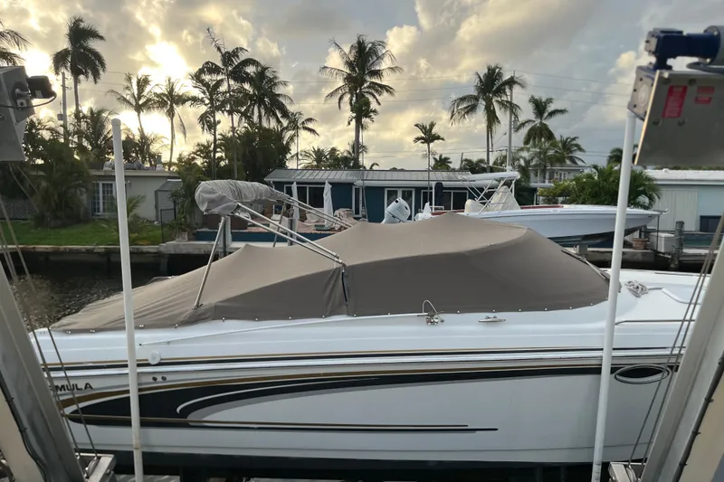 Slide: The Image of 2002 Formula 330 Sun Sport boat docked, covered, with palm trees and sunset in the background. - 59