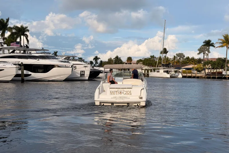 Slide: The Image of 2002 Formula 330 Sun Sport boat cruising in a marina with palm trees and yachts. - 62