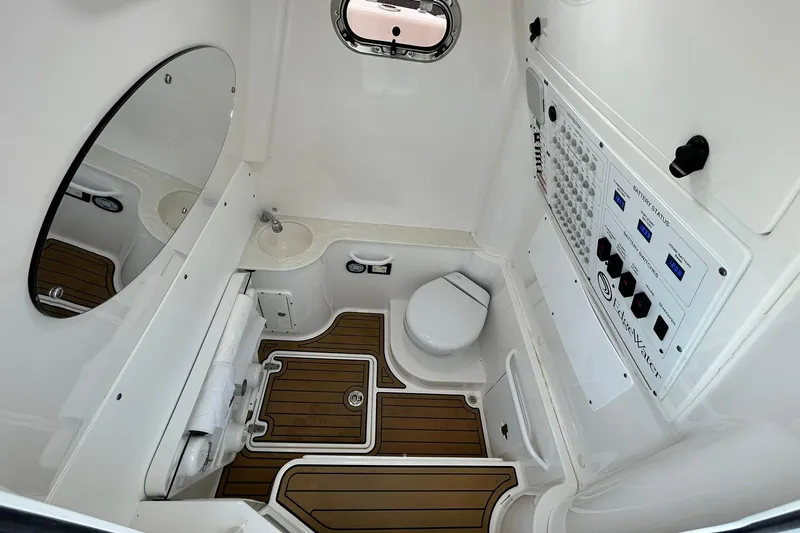 Slide: The Image of 2021 Edgewater 340CC boat interior with control panel, toilet, and wooden flooring. - 26
