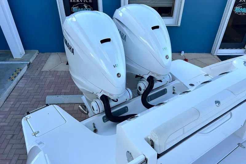 Slide: The Image of 2021 Edgewater 340CC boat with twin Yamaha outboard engines, docked near a blue building. - 3