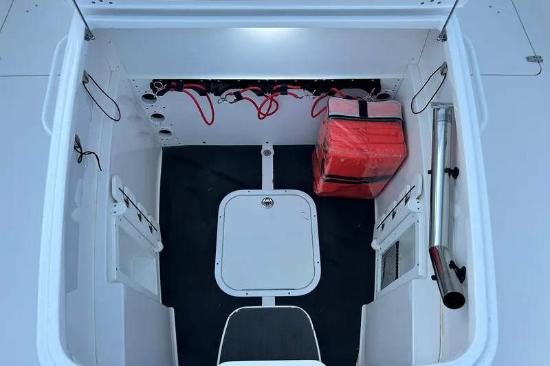 Slide: The Image of 2021 Edgewater 340CC storage compartment with red safety gear and organized cables. - 35