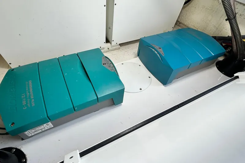 Slide: The Image of Electrical components inside a 2021 Edgewater 340CC boat, featuring two green power units. - 44