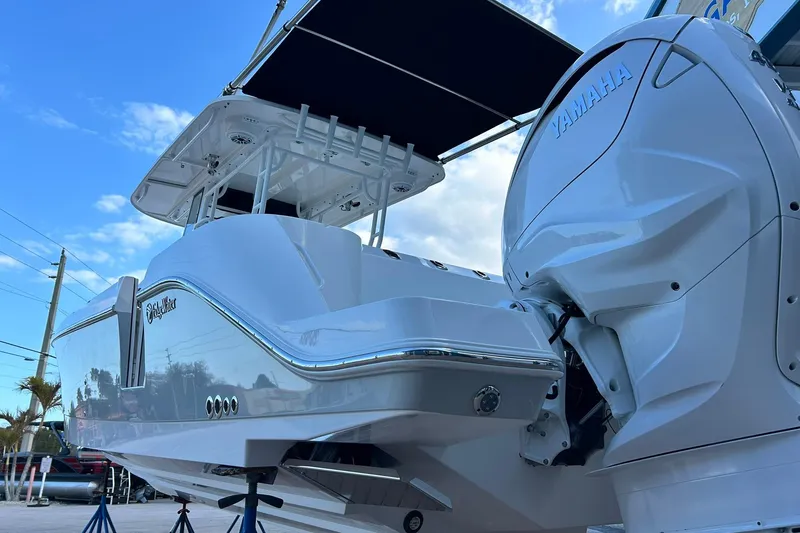 Slide: The Image of 2021 Edgewater 340CC boat with Yamaha engine, docked under a clear blue sky. - 56