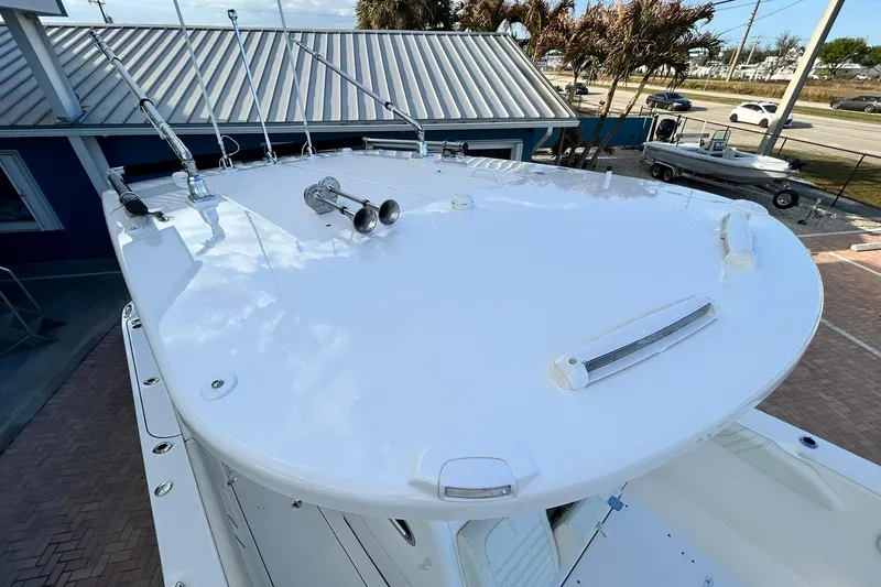 Slide: The Image of 2021 Edgewater 340CC boat roof with fishing rod holders and horn, parked near a building. - 58
