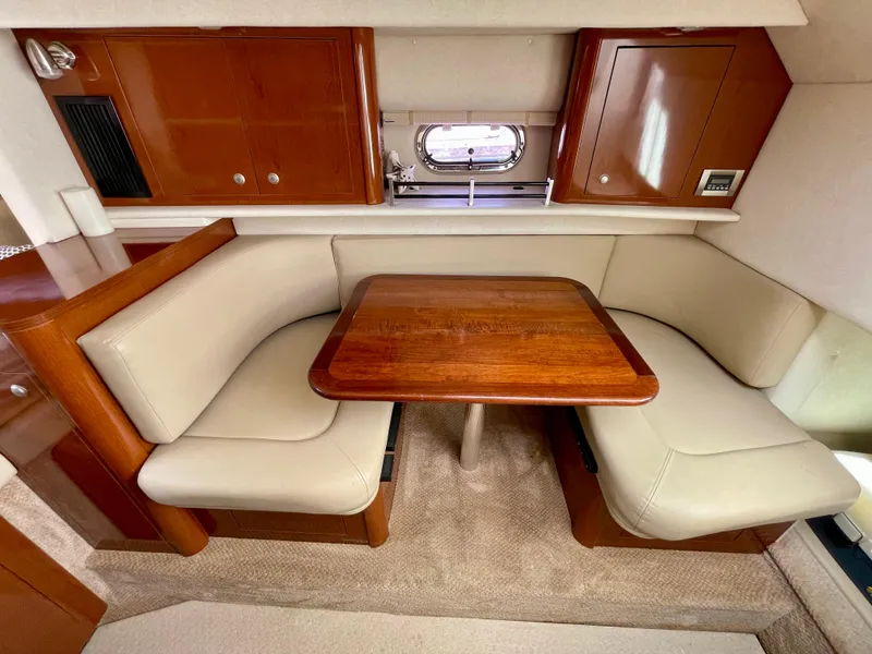 Slide: The Image of 2005 Sea Ray Amberjack 290 interior with beige seating and wooden table. - 10