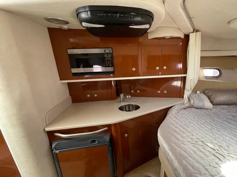 Slide: The Image of 2005 Sea Ray Amberjack 290 interior with kitchenette and bed, featuring wood cabinets and modern appliances. - 11