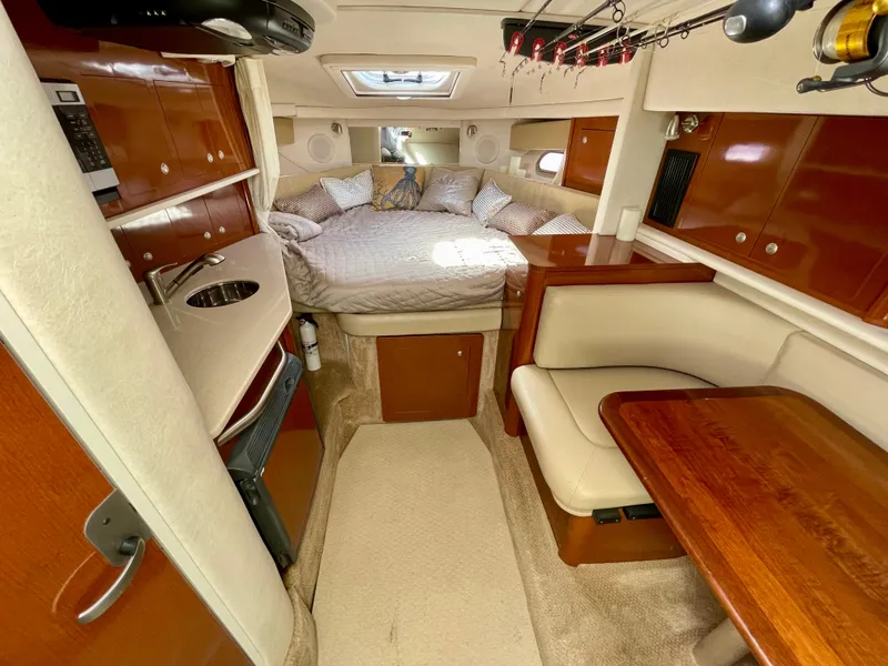 Slide: The Image of 2005 Sea Ray Amberjack 290 cabin interior with bed, kitchenette, and dining area. - 9