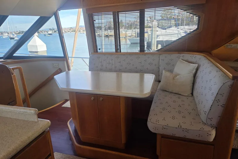 Slide: The Image of 1997 West Bay Sonship yacht interior with dining area, featuring cushioned seating and waterfront view. - 29
