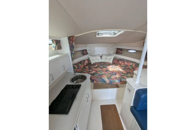 Slide: The Image of 1995 Wellcraft 330 Coastal cabin interior with colorful bedding and compact kitchen area. - 10