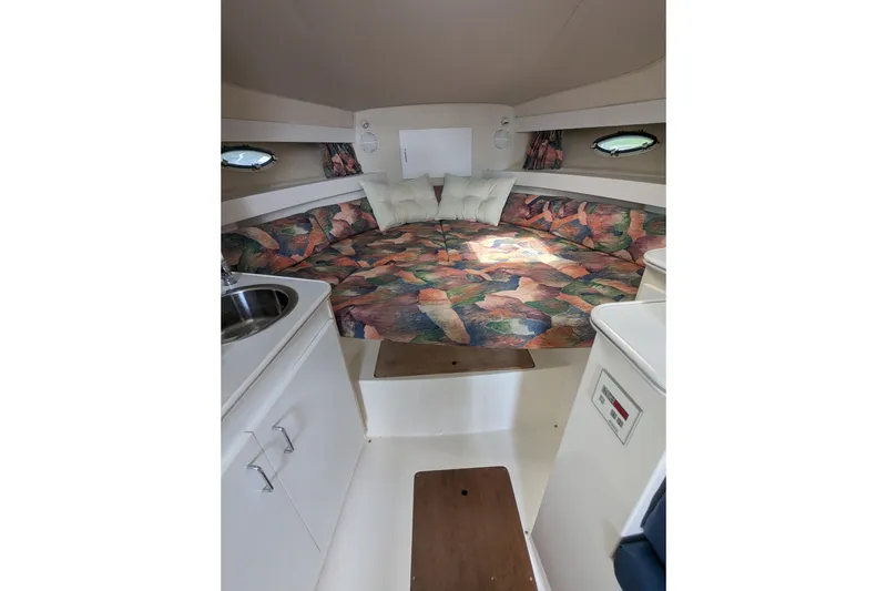 Slide: The Image of 1995 Wellcraft 330 Coastal cabin interior with colorful bedding and compact kitchenette. - 11