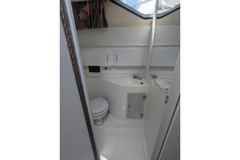 Slide: The Image of 1995 Wellcraft 330 Coastal boat bathroom with toilet, sink, and storage cabinets. - 14