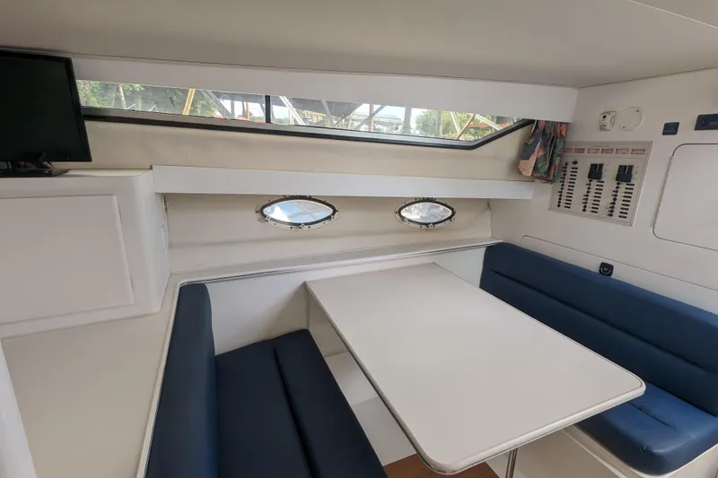 Slide: The Image of 1995 Wellcraft 330 Coastal cabin interior with dining area and blue seating. - 5