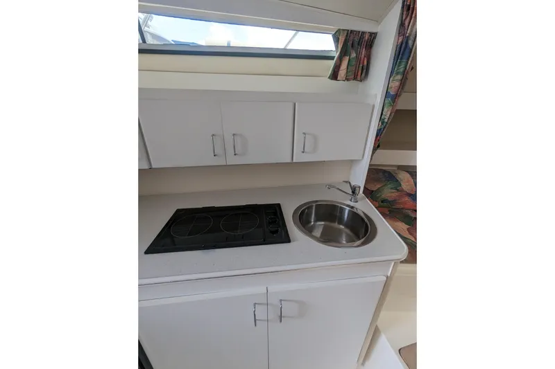 Slide: The Image of 1995 Wellcraft 330 Coastal boat kitchenette with stove, sink, and storage cabinets. - 9