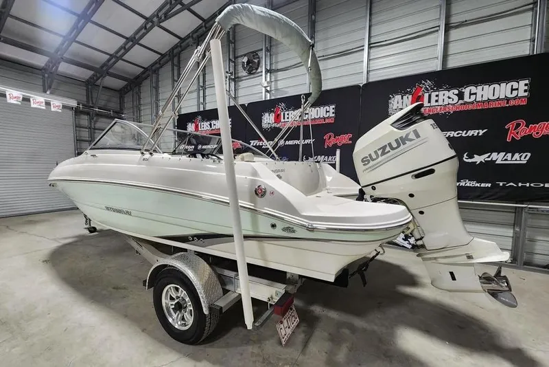 Slide: The Image of 2017 Stingray 201 DC boat with Suzuki outboard motor in a showroom setting. - 2