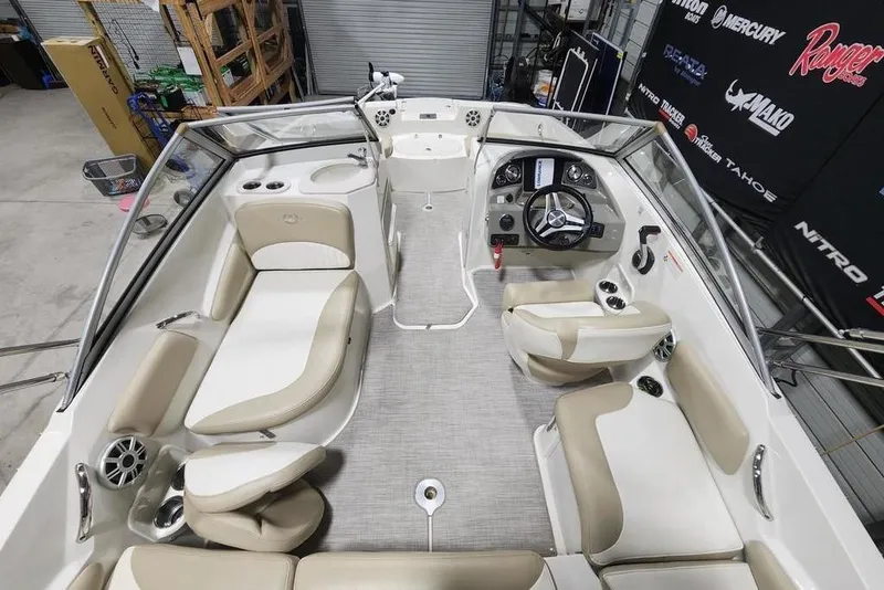 Slide: The Image of 2017 Stingray 201 DC boat interior with beige seating and modern dashboard in a showroom. - 3