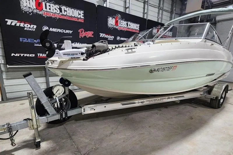Slide: The Image of 2017 Stingray 201 DC boat on trailer in showroom with promotional banners. - 8