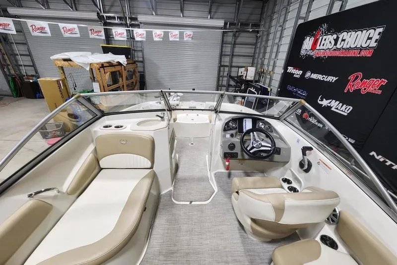 Slide: The Image of 2017 Stingray 201 DC boat interior with beige seating and steering console in showroom. - 9