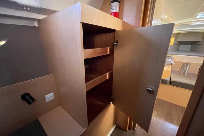 Slide: The Image of Interior of 2015 Beneteau First 235 sailboat with open wooden cabinet and fire extinguisher. - 29