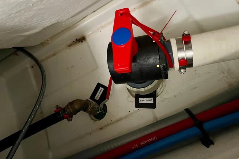 Slide: The Image of Boat plumbing system with red valve, labeled "Toilet Outlet," in a 2015 Beneteau First 235. - 35