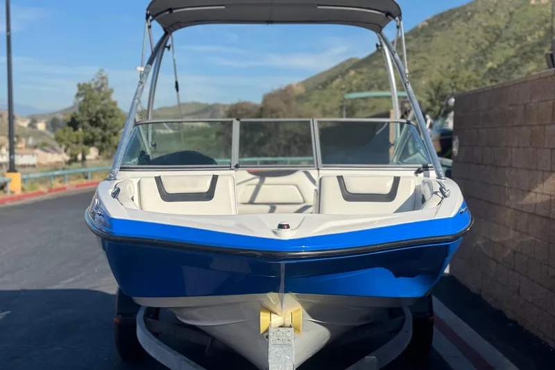 Slide: The Image of 2015 Yamaha Boats AR190, blue and white, parked on a trailer with scenic background. - 2